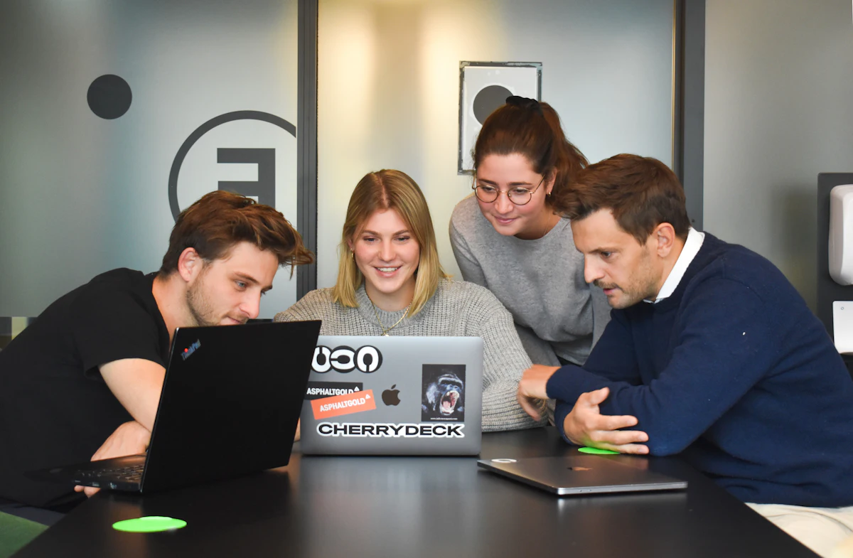 Four people discussing a project at a laptop in a modern office